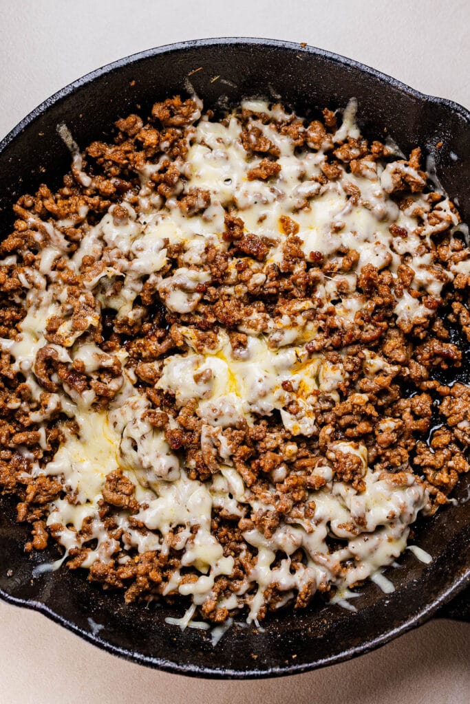 This a photo of cheesey beef in a black pan.