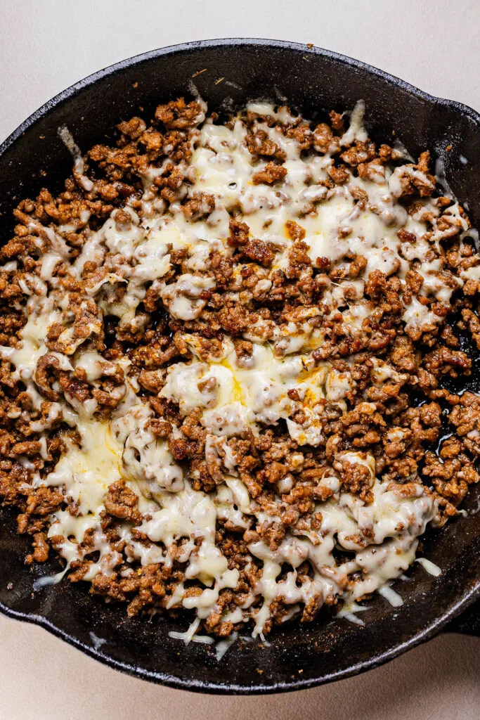 This a photo of cheesey beef in a black pan.