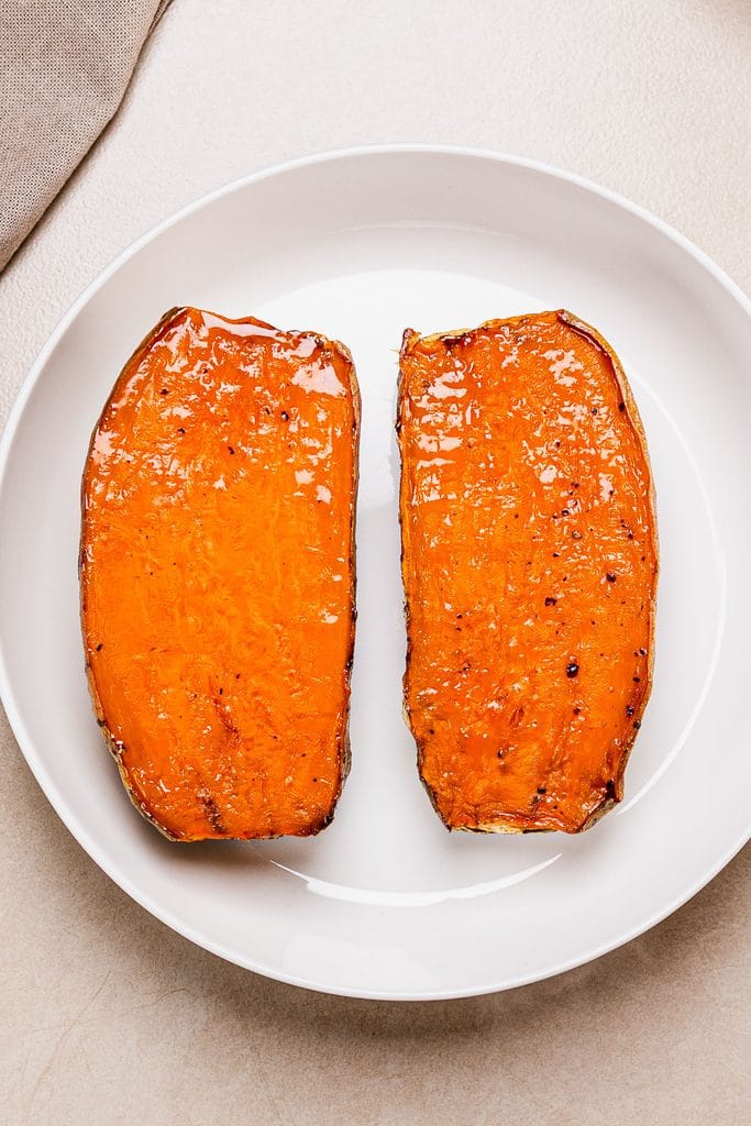 Baked halved sweet potatoes in a white plate.