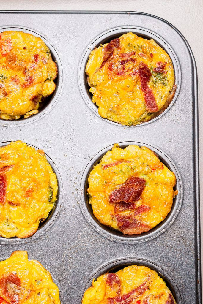 Bacon broccoli egg muffins with cottage cheese, cheddar cheese, chopped bacon, and diced red bell peppers.
