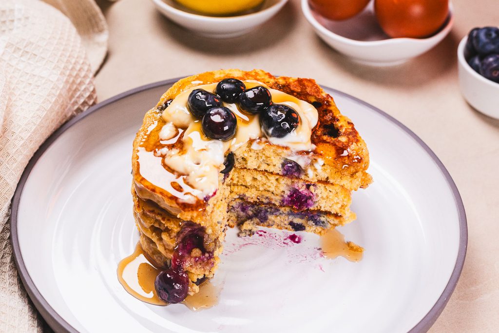 High protein blueberry pancakes served with Greek yogurt, fresh blueberries, and maple syrup for a delicious breakfast.