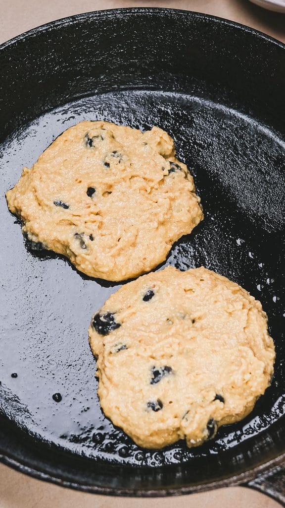 Blueberry protein pancakes cooking in a non-stick skillet until golden brown and fluffy.