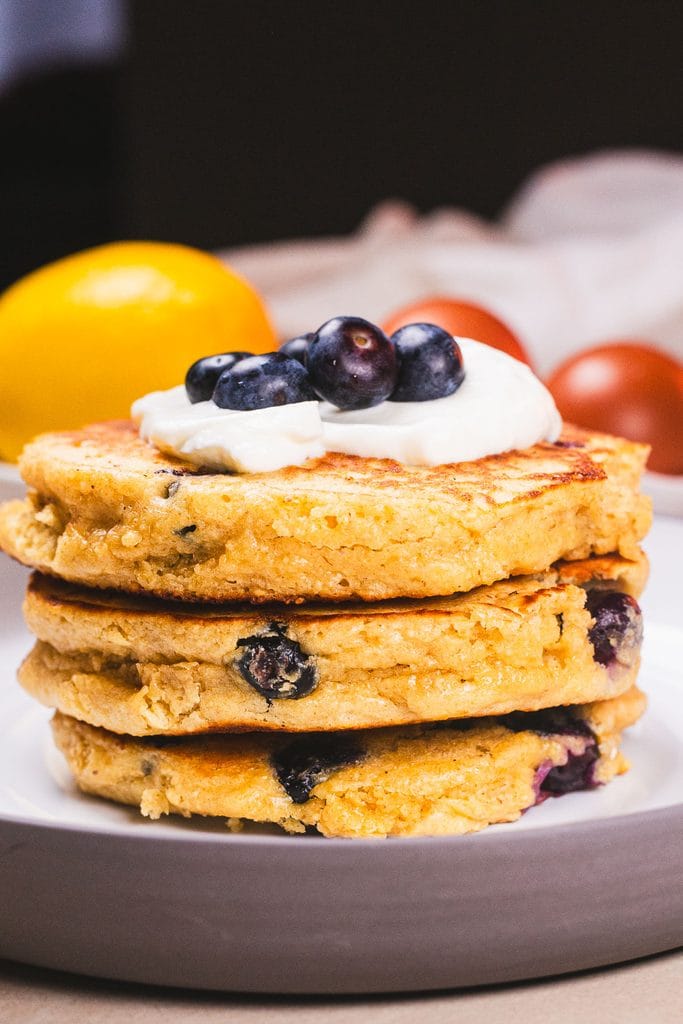 A stack of fluffy high protein blueberry pancakes topped with juicy blueberries, ready to serve for breakfast.
