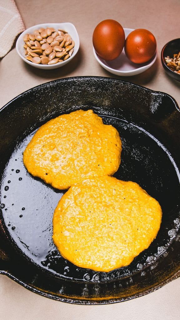 Protein pumpkin pancakes cooking in a skillet
