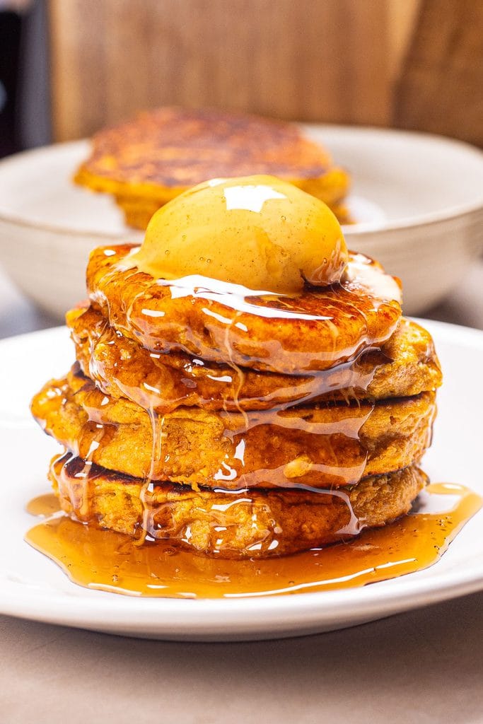 Stack of high protein pumpkin pancakes topped with spiced butter and syrup.
