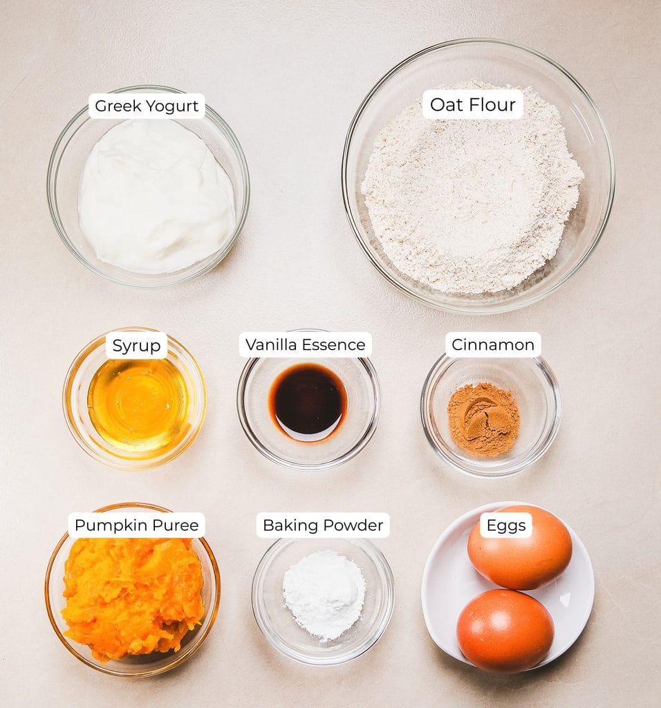 Ingredients for homemade protein pumpkin pancakes including pumpkin puree, eggs, yogurt, and oats